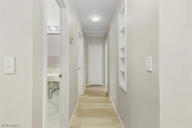 a view of a hallway with wooden floor and a bathroom