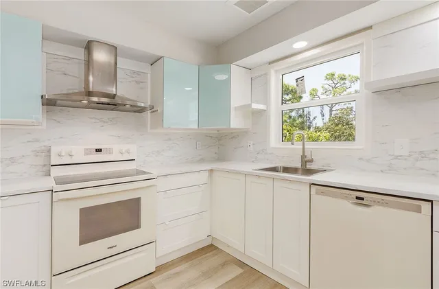 a kitchen with granite countertop white cabinets white appliances sink and window