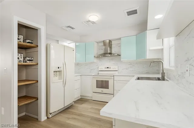 a large white kitchen with a sink and dishwasher a refrigerator with white cabinets
