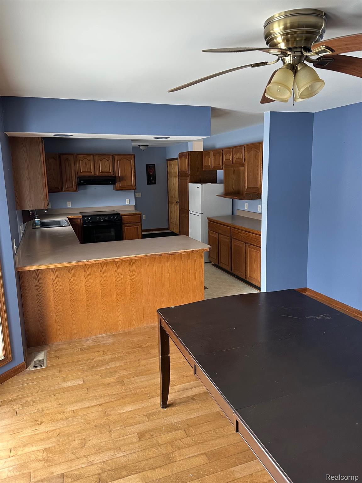 3803 Warner Road Cass City, MI 48726 - Photo 51 of 85 Kitchen with ceiling fan, a peninsula, freestanding refrigerator, black range with electric stovetop, and brown cabinetry