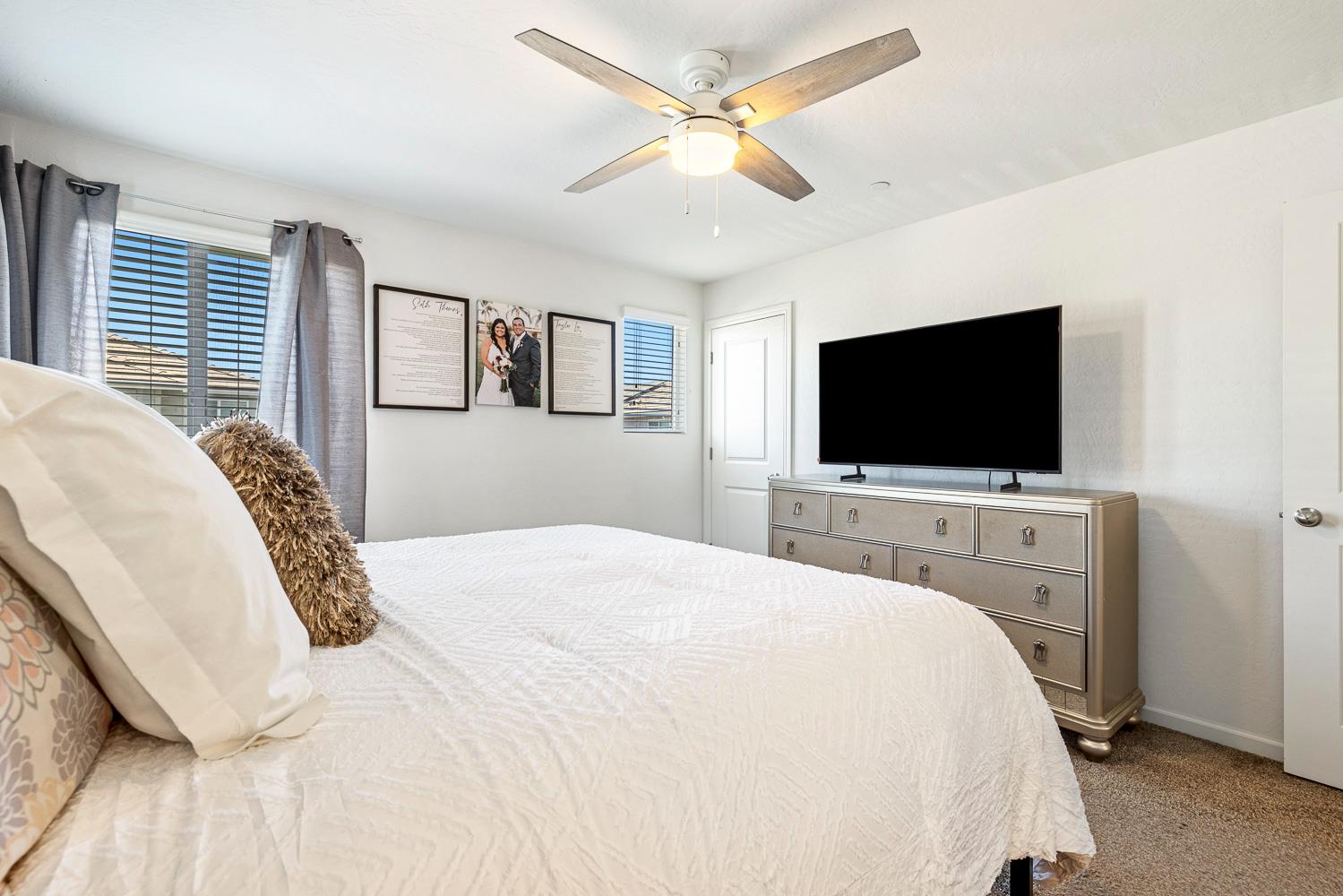 3780 Highclere Way Clovis, CA 93619 - Photo 10 of 21 a bedroom with a bed tv and a chandelier