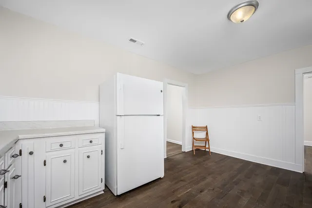 a view of a kitchen with refrigerator and wooden floor