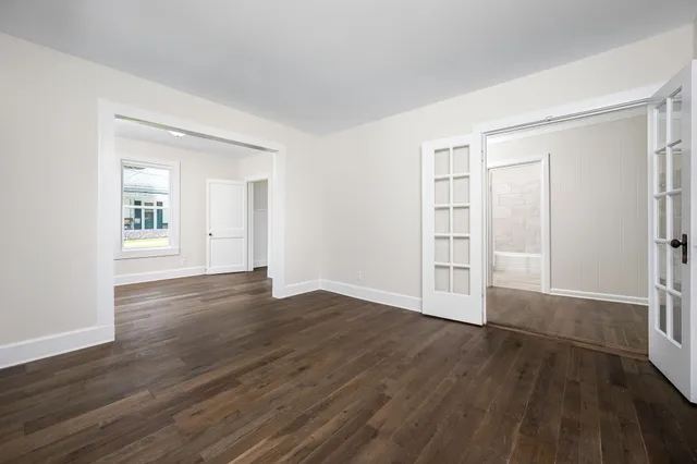 an empty room with wooden floor & windows