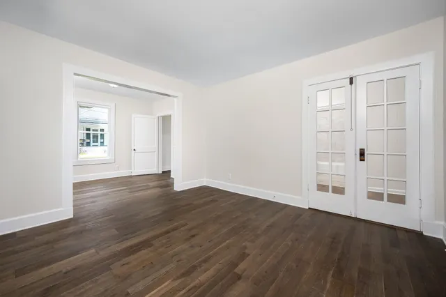 an empty room with wooden floor closet and windows