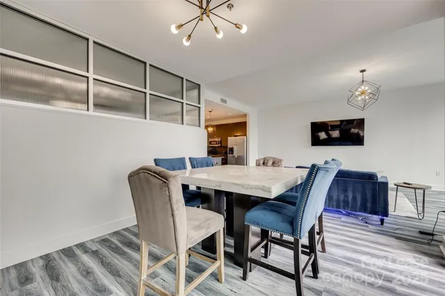 a living room with furniture and a table with kitchen view with wooden floor
