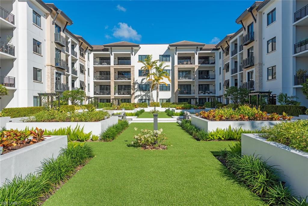 1135 3rd Avenue South, Unit 308 Naples, FL 34102 - Photo 16 of 18 a front view of a building with a yard and potted plants