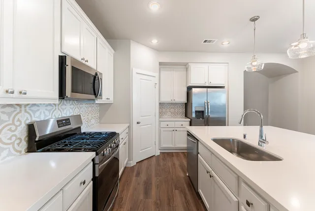 a kitchen with stainless steel appliances granite countertop a sink stove and refrigerator