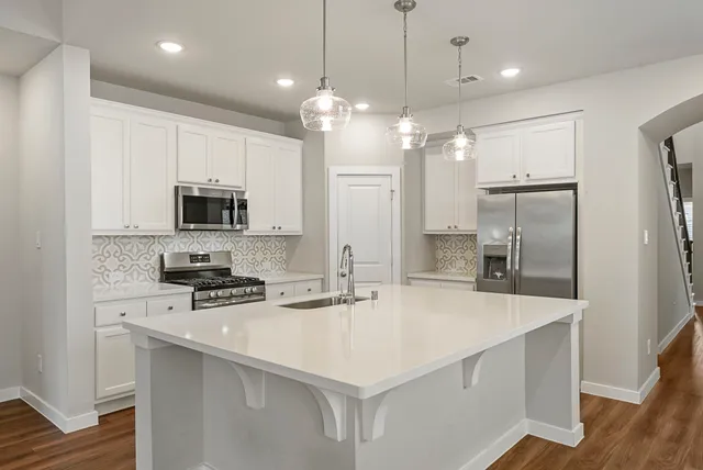 a kitchen with stainless steel appliances a stove a sink and a refrigerator