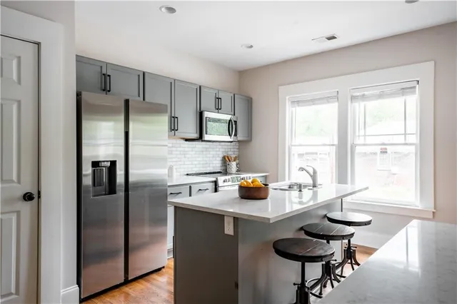 a kitchen with stainless steel appliances granite countertop a refrigerator a sink a stove and a refrigerator with wooden floor