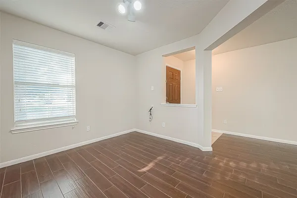a view of an empty room with wooden floor and a window
