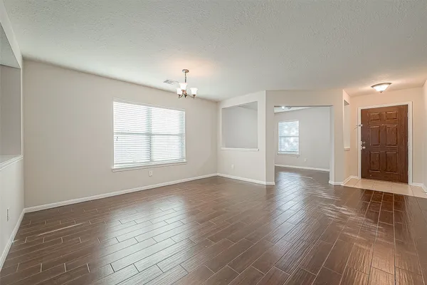 an empty room with wooden floor chandelier and windows