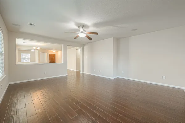 a view of an empty room with a window and wooden floor