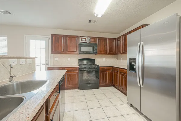 a kitchen with a refrigerator sink and wooden cabinets