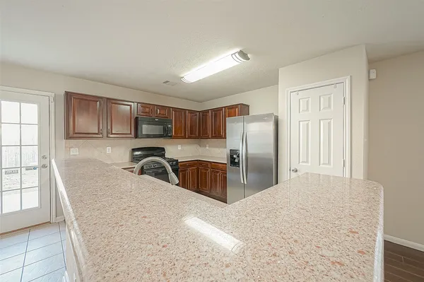 a kitchen with stainless steel appliances granite countertop a refrigerator a sink a stove with wooden cabinets