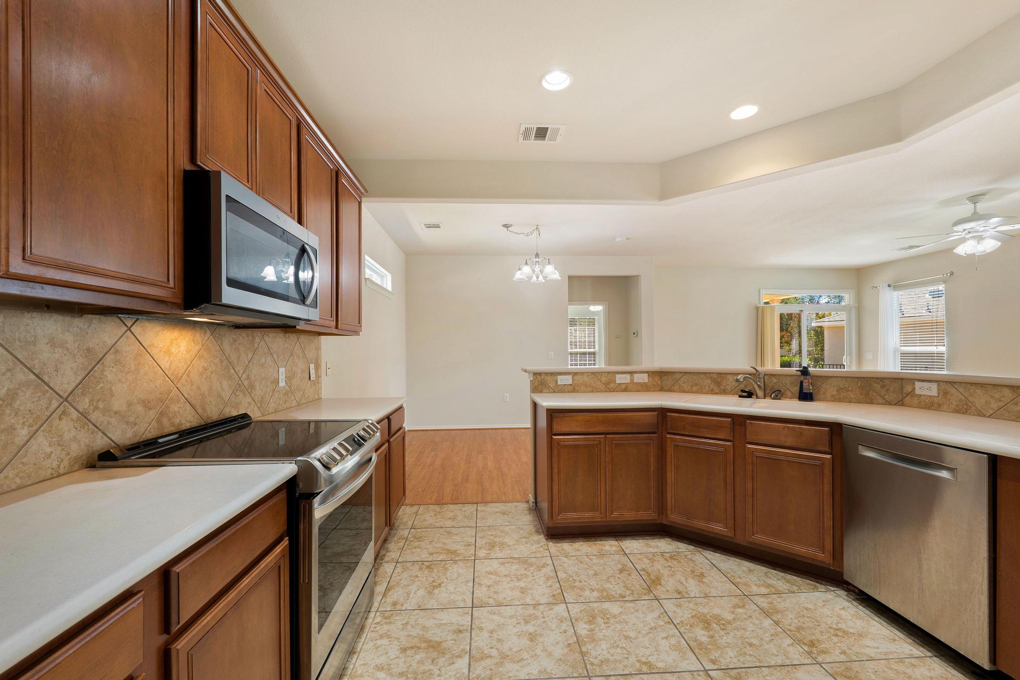 520 Mill Pond Path Georgetown, TX 78633 - Photo 18 of 38 A well-equipped kitchen features ample cabinetry, stone countertops, and a full suite of stainless steel appliances.