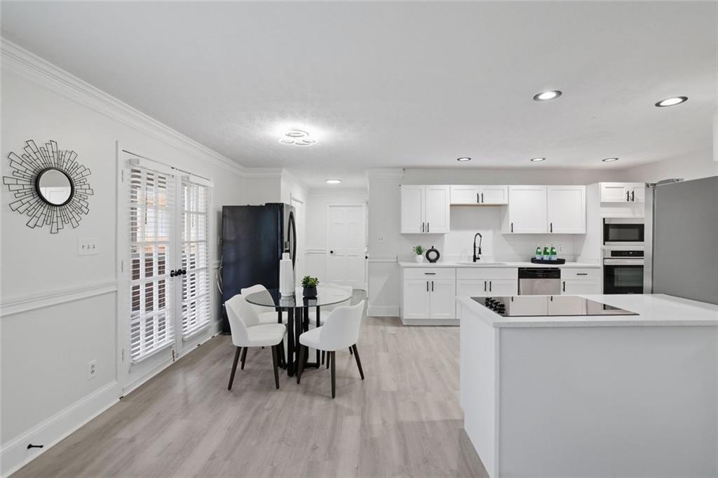 4645 Riveredge Cove Snellville, GA 30039 - Photo 14 of 43 a living room with stainless steel appliances furniture a dining table wooden floor and a rug