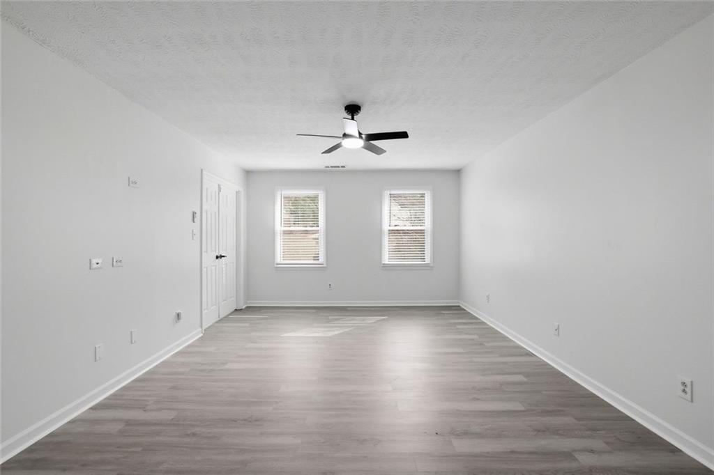 4645 Riveredge Cove Snellville, GA 30039 - Photo 27 of 43 an empty room with wooden floor chandelier fan and windows
