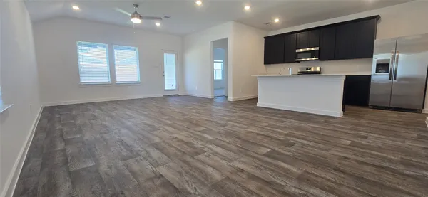 a view of kitchen with stainless steel appliances wooden floor and large window