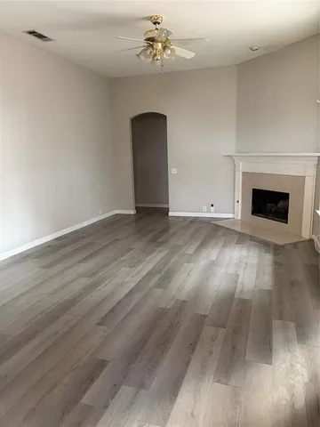 a view of an empty room with wooden floor and a fireplace