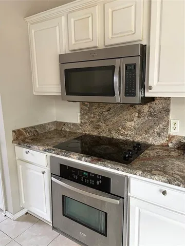 a kitchen with granite countertop white cabinets and stainless steel appliances