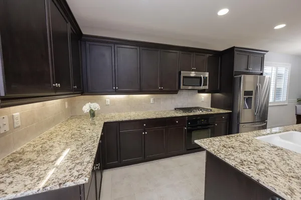 a kitchen with stainless steel appliances granite countertop a table chairs sink refrigerator and microwave
