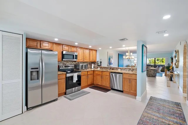 a large kitchen with granite countertop a large counter top stainless steel appliances and cabinets