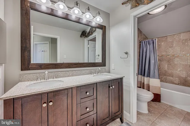 a bathroom with a double vanity sink and mirror with toilet