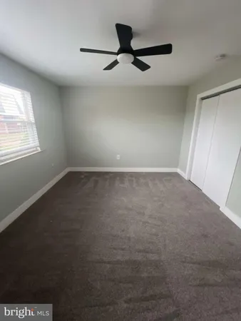 an empty room with a ceiling fan and window