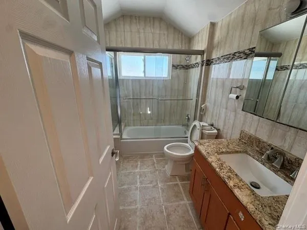 a bathroom with a granite countertop sink a toilet and shower