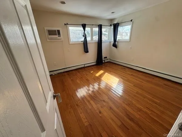 a view of empty room with window and wooden floor