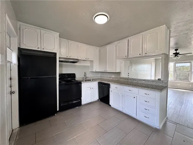 a kitchen with granite countertop white cabinets and refrigerator