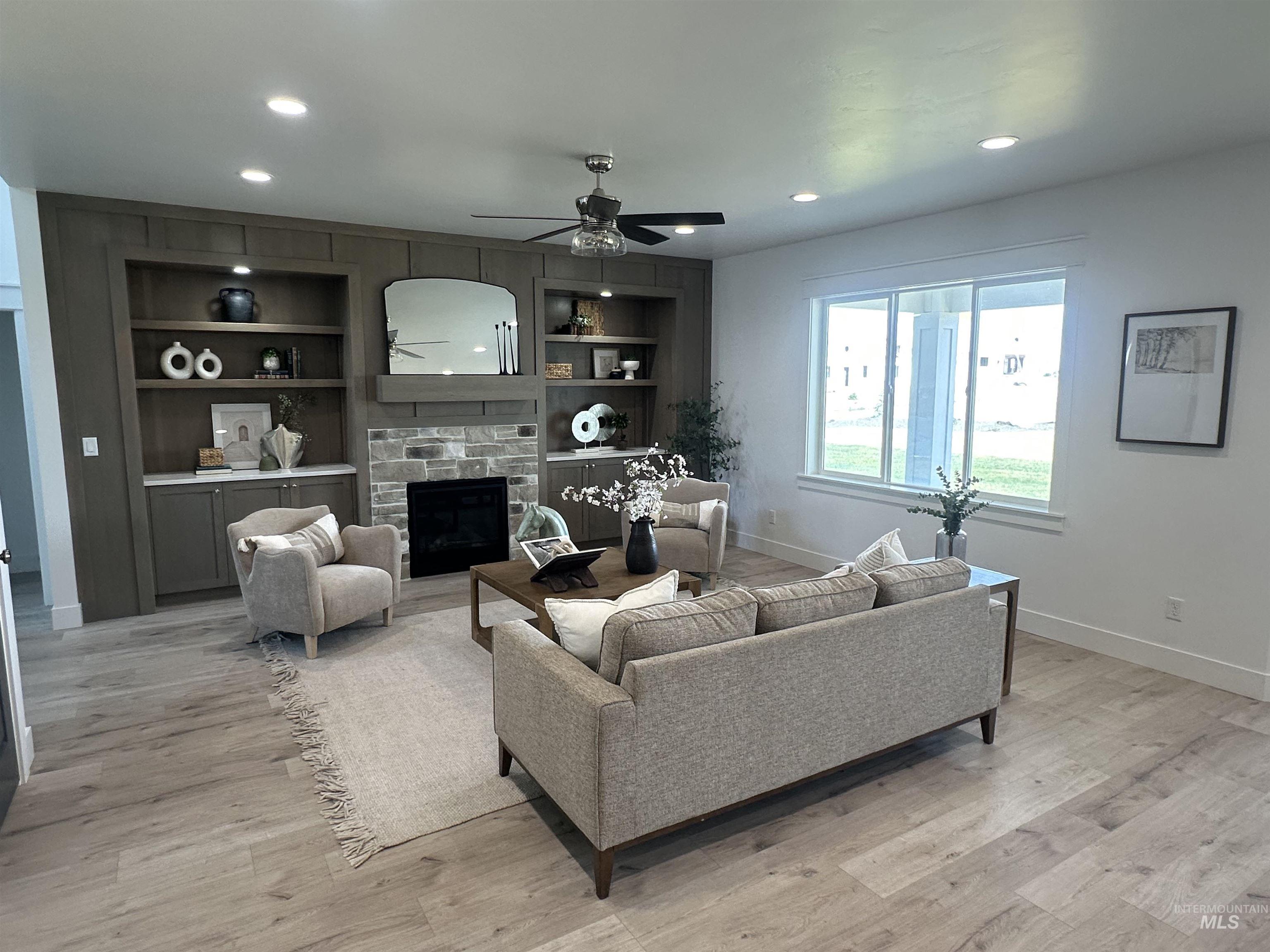 3035 Lake View Twin Falls, ID 83301 - Photo 7 of 41 Living area featuring a stone fireplace with a wood mantle, built-in cabinetry with open shelving, wood-finish flooring, and recessed lighting