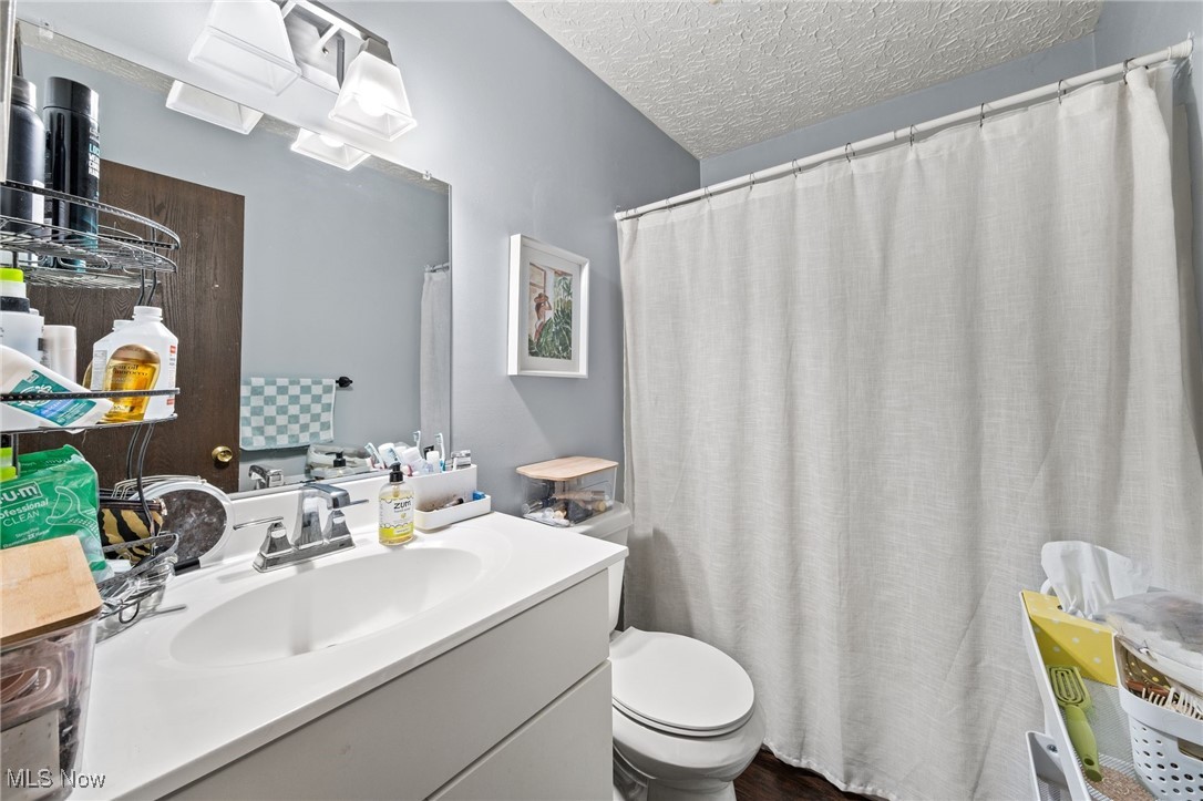 3213-3217 Pickle Road Green, OH 44312 - Photo 28 of 41 Full bath with a shower with shower curtain, a textured ceiling, and vanity