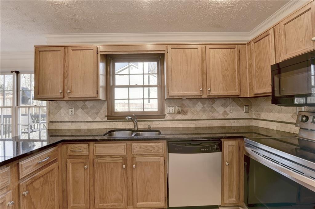 3945 Genoa Court Duluth, GA 30096 - Photo 22 of 64 a kitchen with granite countertop white cabinets and black appliances