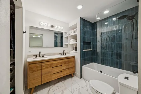 a bathroom with a bathtub shower sink vanity mirror and toilet