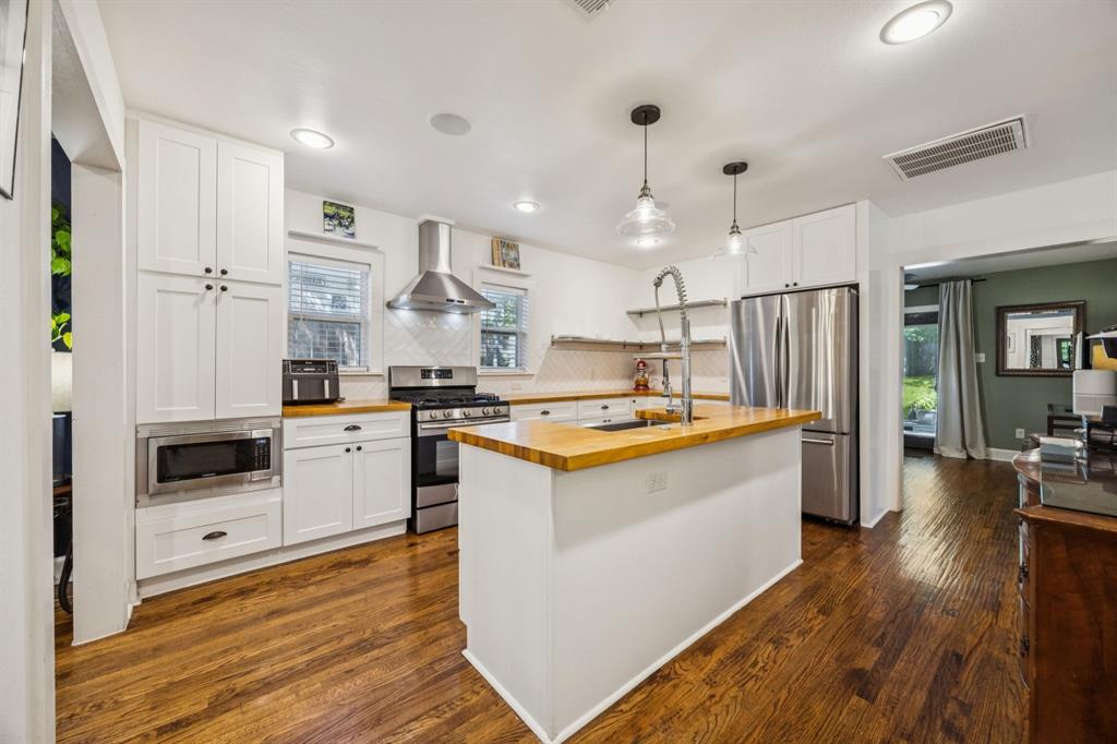 1227 Lansford Avenue Dallas, TX 75224 - Photo 3 of 17 a white kitchen with wooden floor and stainless steel appliances