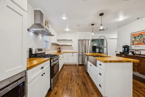a large kitchen with stainless steel appliances granite countertop a lot of cabinets and wooden floor