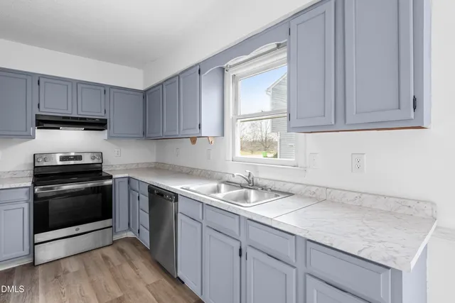 a kitchen with granite countertop a sink stainless steel appliances and cabinets