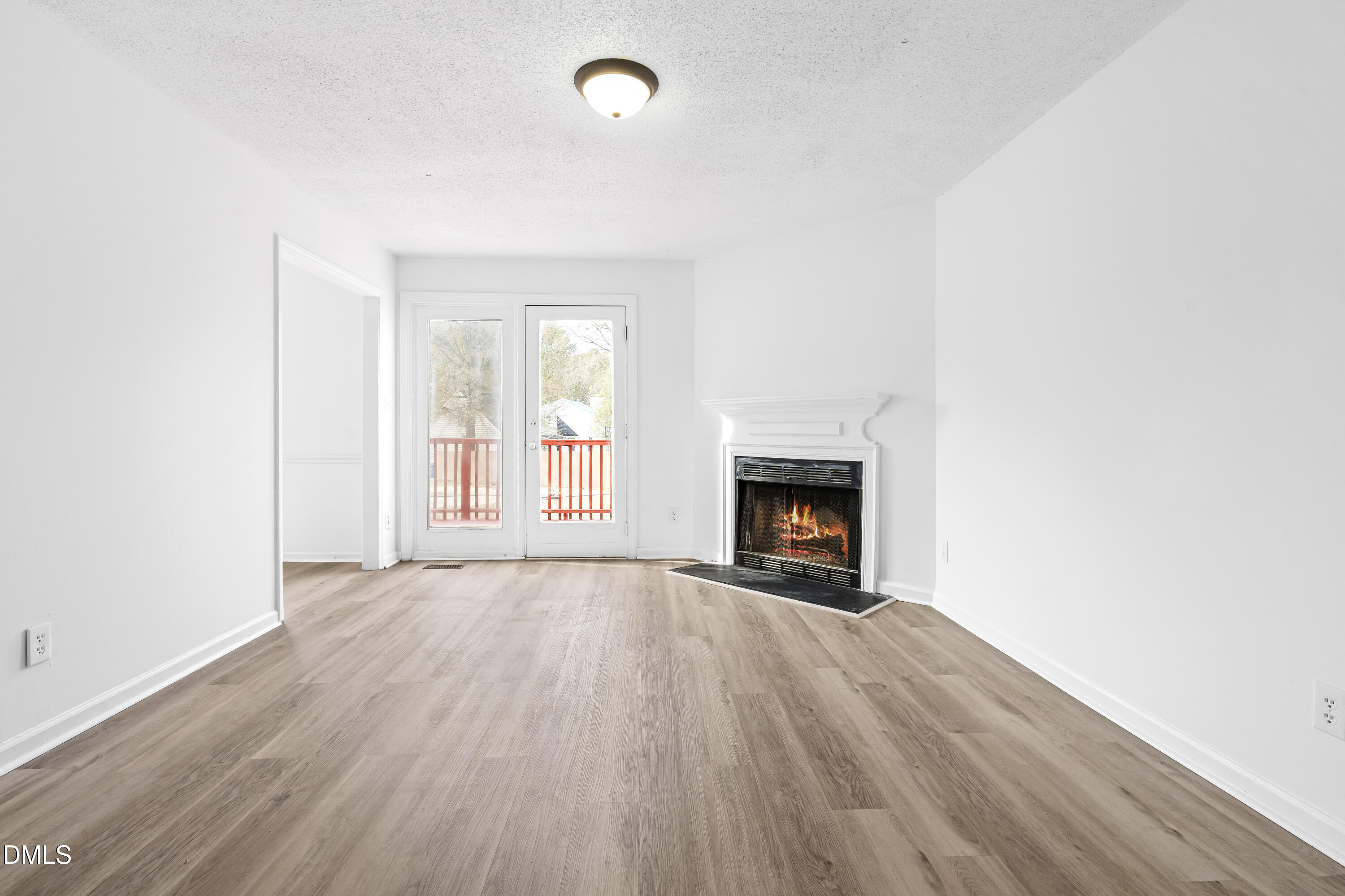 8029 Perry Creek Road Raleigh, NC 27616 - Photo 9 of 27 an empty room with wooden floor fireplace and windows