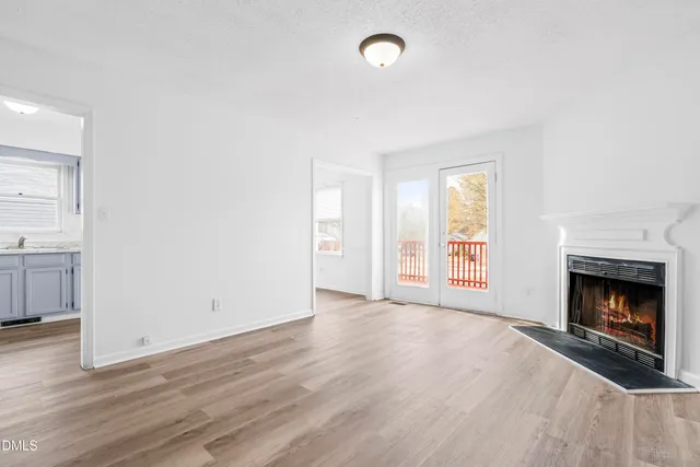 an empty room with wooden floor fireplace and windows