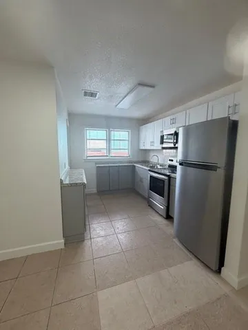 a kitchen with granite countertop a refrigerator and a stove top oven