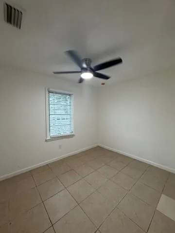 an empty room with a ceiling fan and window