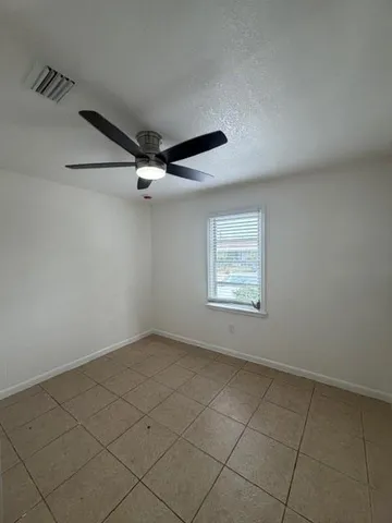 an empty room with a ceiling fan and window