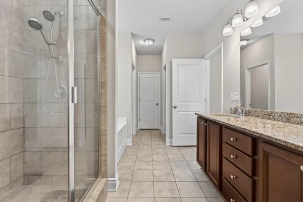 a bathroom with a double vanity sink a large mirror and shower