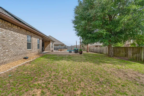 a backyard of a house with wooden fence and large trees
