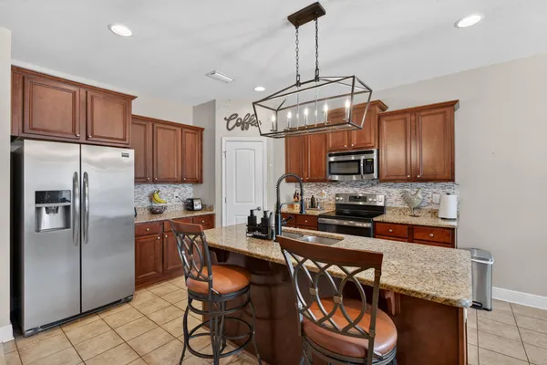 a kitchen with granite countertop stainless steel appliances a table chairs microwave and refrigerator