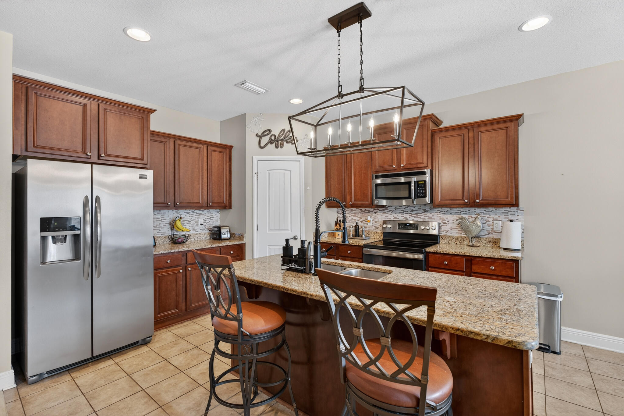 511 Gadwell Street Crestview, FL 32539 - Photo 7 of 48 a kitchen with granite countertop stainless steel appliances a table chairs microwave and refrigerator