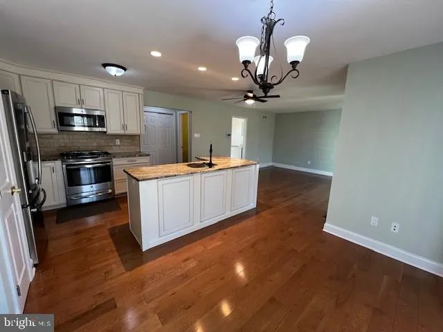 a kitchen with stainless steel appliances a large counter top a sink a stove and a refrigerator