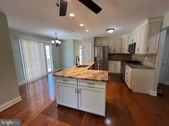 a kitchen with kitchen island granite countertop wooden floors stainless steel appliances and sink