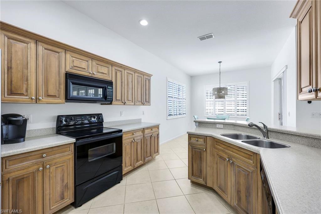 9375 Oak Strand Drive Estero, FL 34135 - Photo 11 of 30 a kitchen with stainless steel appliances granite countertop a sink stove and cabinets